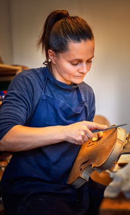 Judith Bauer feilt die Ränder einer Geige ab.